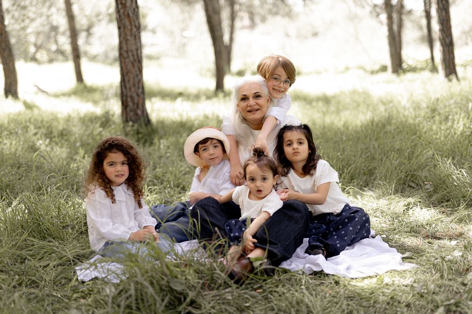 סבתא ונכדים יושבים יחד על הדשא ביער